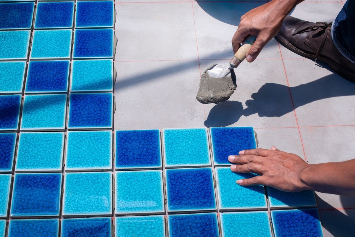 A worker putting tiles at home repair, installation of tiles on the glue, with trowel in hand