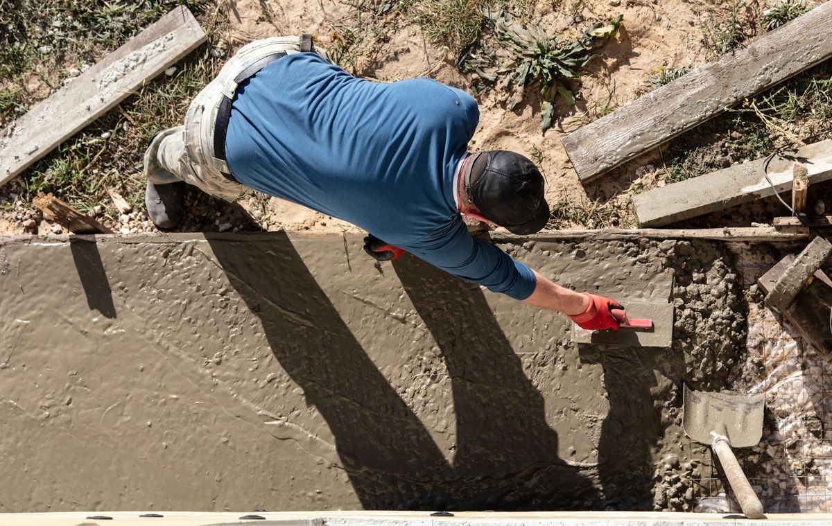 Workers pour concrete solution at a construction site .